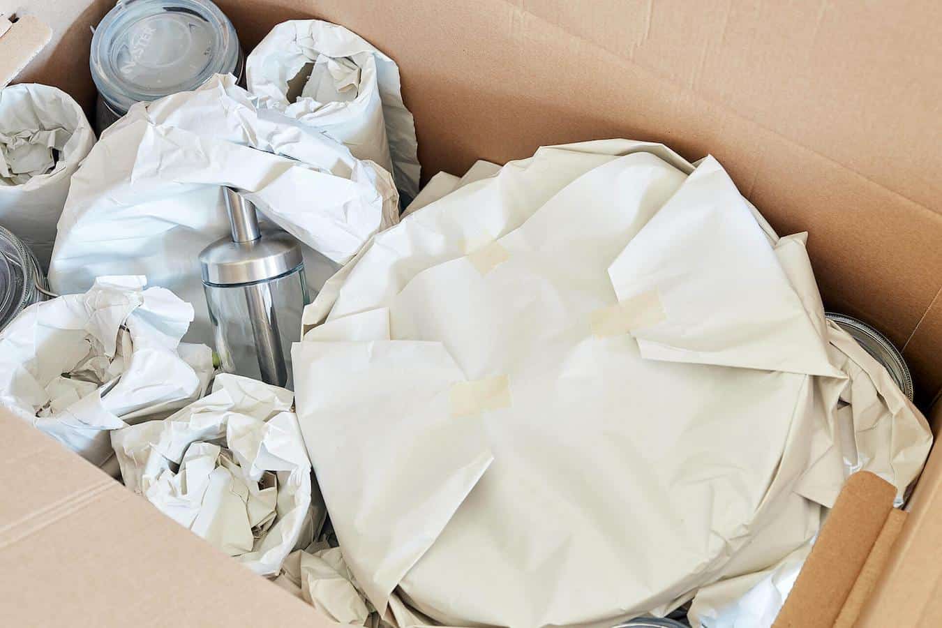 a moving box full of dishes wrapped in packing paper wrapping paper a few plates unused plates small box extra space family heirlooms dining room paper inside fragile items bubble wrap pack dishes box pack box